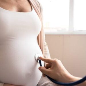 Médico revisa el vientre de una mujer embarazada, mostrando la importancia del cuidado emocional y físico durante la gestación.