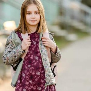 Niña de unos 8 años con mochila caminando al colegio, ilustrando señales de pubertad temprana en niñas.