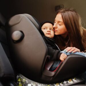 Madre asegurando a su bebé en una silla de auto para un viaje largo.