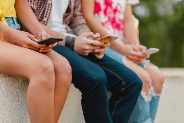 Cuatro adolescentes viendo su celular mostrando la importancia de poner limites sanos.