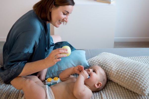 Mamá cuidando a su bebé de manera cercana para prevenir accidentes cuando se mete cosas a la boca.